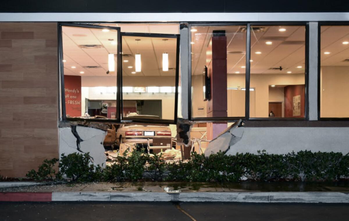 A broken exterior wall of a Wendy's, with a vehicle inside the restaurant's dining room