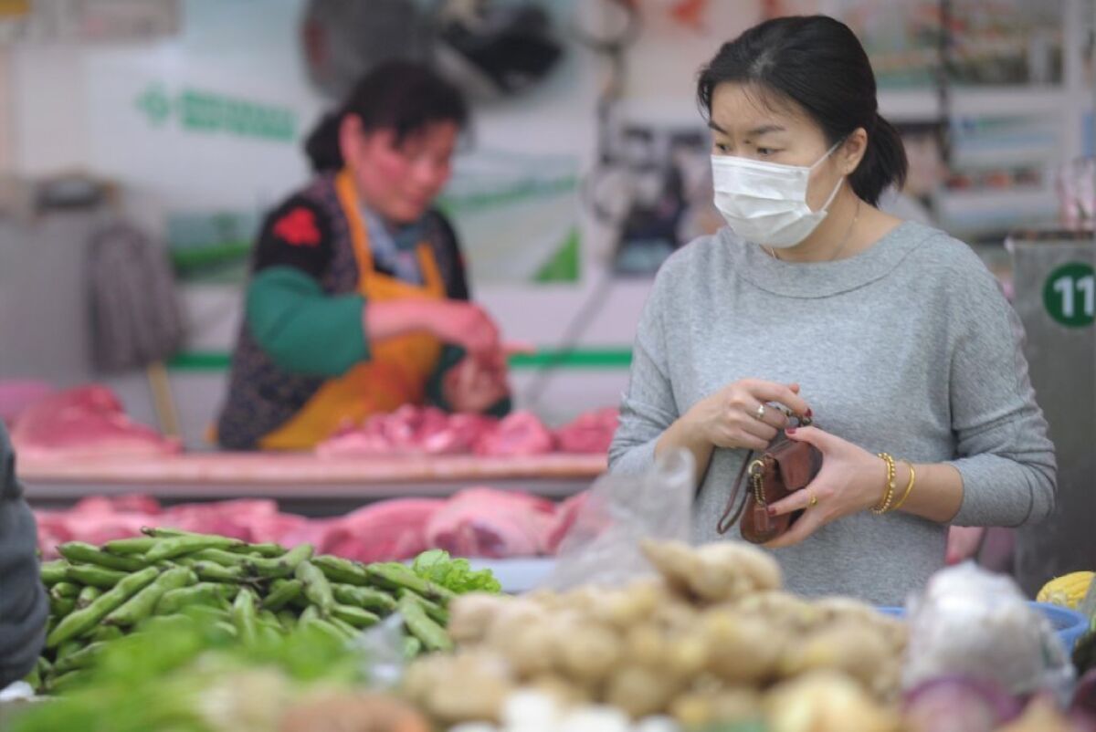 A woman wears a mask as she shops in a market in Shanghai in April. Bird flu has Chinese shoppers fearful of poultry. Now a three-month national campaign has found rat and other uninspected meats disguised as beef and mutton.