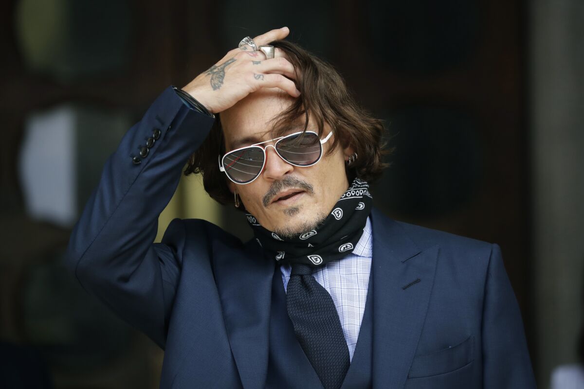 FILE - In this Tuesday, July 14, 2020 file photo, American actor Johnny Depp gestures to the media as he arrives at the High Court in London. The UK High Court has ruled against Johnny Depp in his libel suit against the owner of the Sun newpaper over wife-beating allegation, it was reported on Monday, Nov. 2, 2020. (AP Photo/Matt Dunham, file)