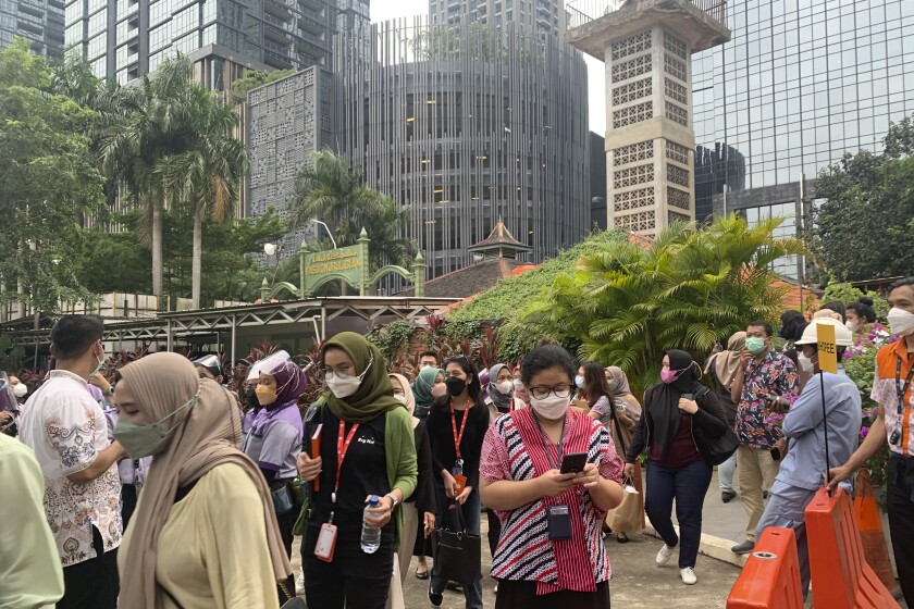 People wait outside as they have to evacuate their office buildings following an earthquake, at the main business district in Jakarta, Indonesia, Friday, Jan. 14, 2022. A powerful earthquake shook parts of Indonesia's main island of Java on Friday, causing buildings in the capital to sway, but there were no immediate reports of serious damage or casualties. Officials said there was no danger of a tsunami. (AP Photo/Tatan Syuflana)