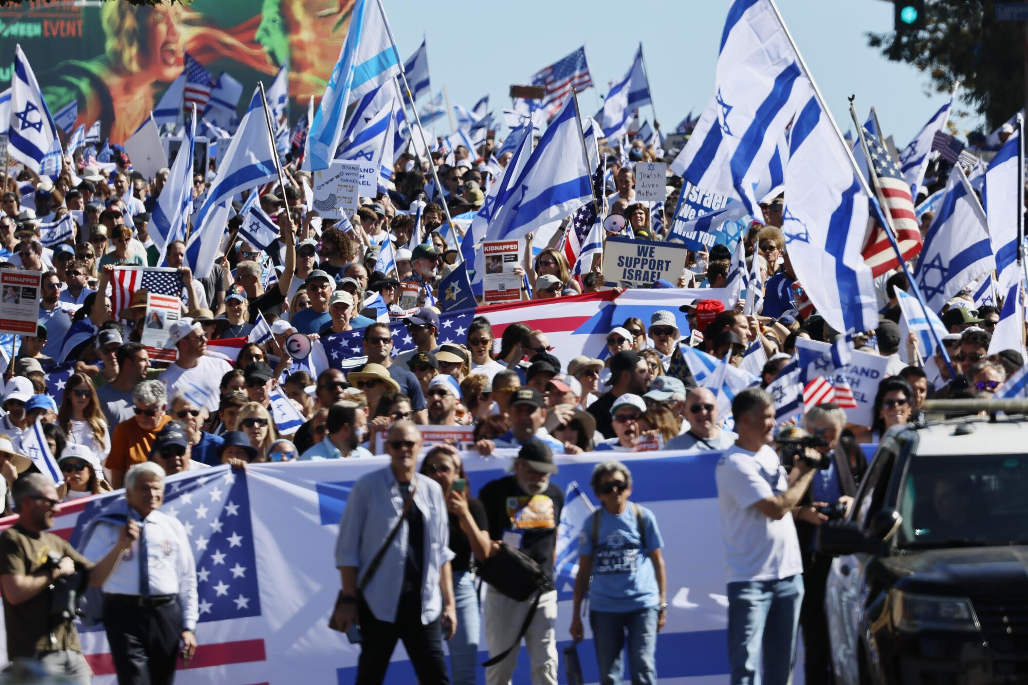 A large crowd waving blue-and-white flags and the U.S. flag 
