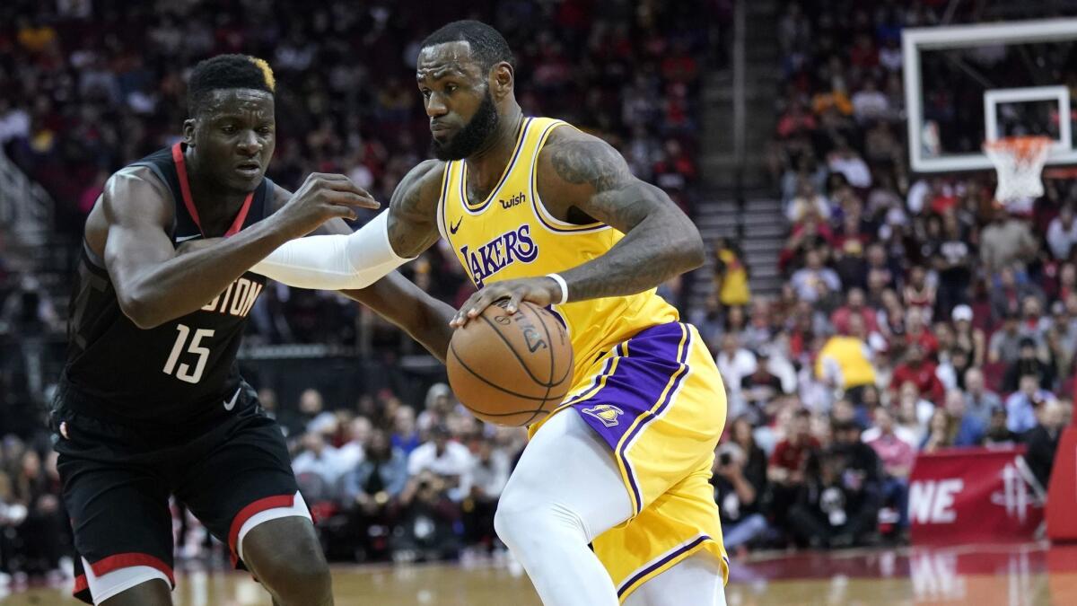 Lakers' LeBron James, right, drives toward the basket as Houston Rockets' Clint Capela (15) defends during the first half.