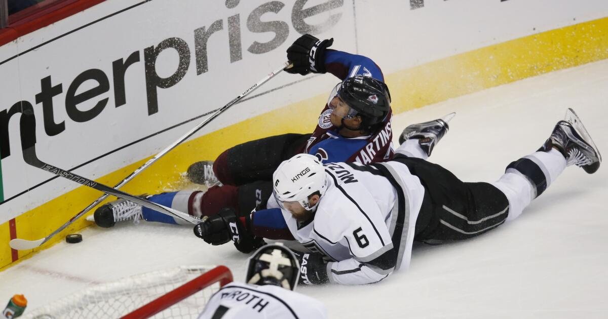 Kings defenseman Jake Muzzin (6) slides into the boards with Avalanche center Andreas Martinsen while pursuing the puck in the third period.