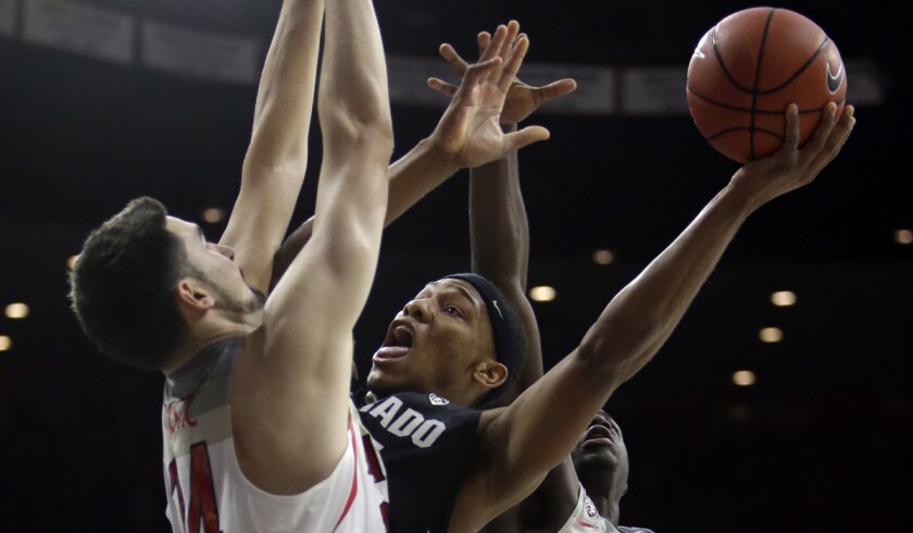 Colorado guard George King tries to shoot over Arizona center Dusan Ristic on Saturday.