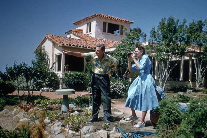 American writer and illustrator Dr Seuss points  while his wife Helen prepares to take a picture.