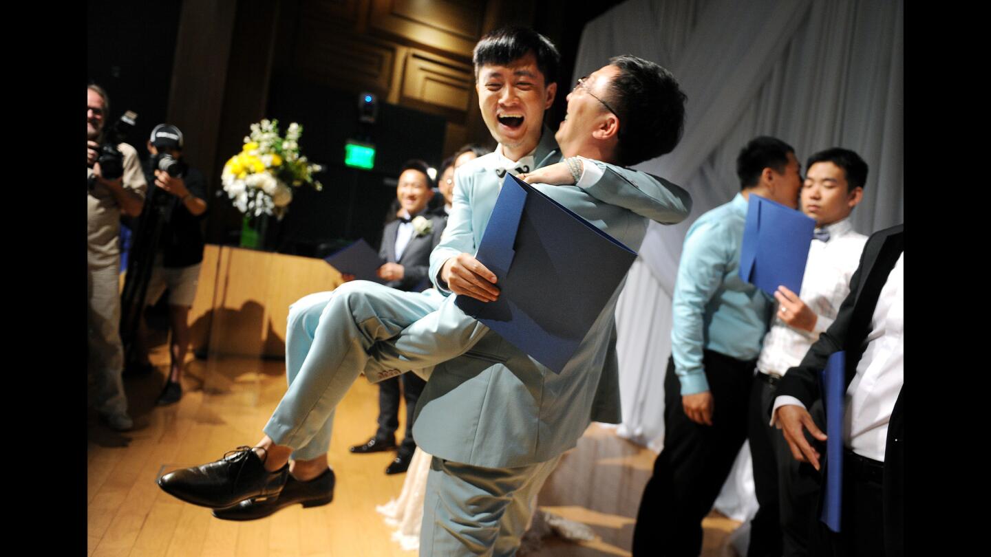 Shanghai resident Li Tao, 30, is lifted by his new husband, Duan Rongfeng, 38, one of seven Chinese same-sex couples married in a group wedding ceremony that was officiated by West Hollywood Mayor Lindsey Horvath at the West Hollywood Library.