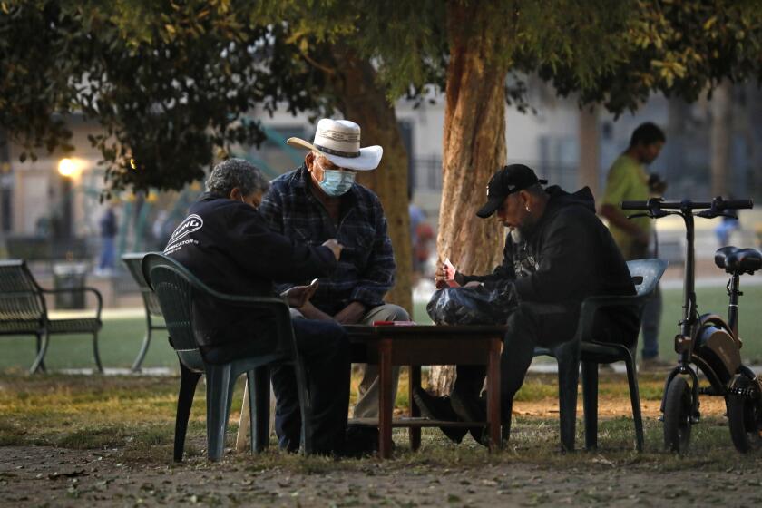 Los Angeles, California-Nov. 19, 2020-California will impose "limited" curfew due to COVID-19 surge. People gather outside, some playing cards, at MacArthur Park on Nov. 19, 2020 at 5:00pm. (Carolyn Cole / Los Angeles Times)