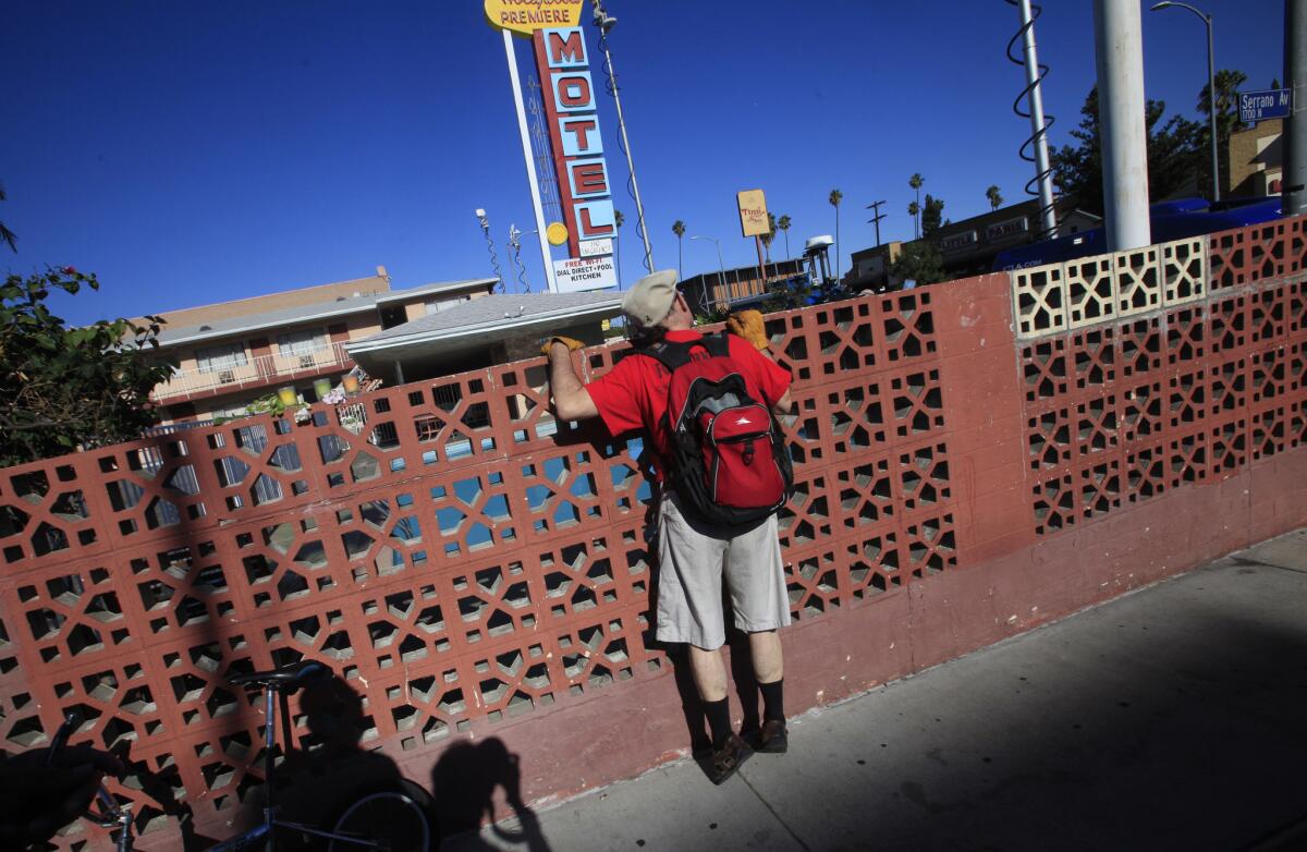 Dave Cantos of Hollywood looks over the fence at a Hollywood motel where an woman and two children were pulled from a pool. They were listed in grave condition.