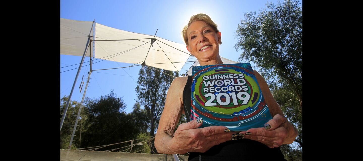 Betty Goedhart, 85, holds the 2019 Guinness World Records book that has her listed as the oldest performing female flying trapeze artist.
