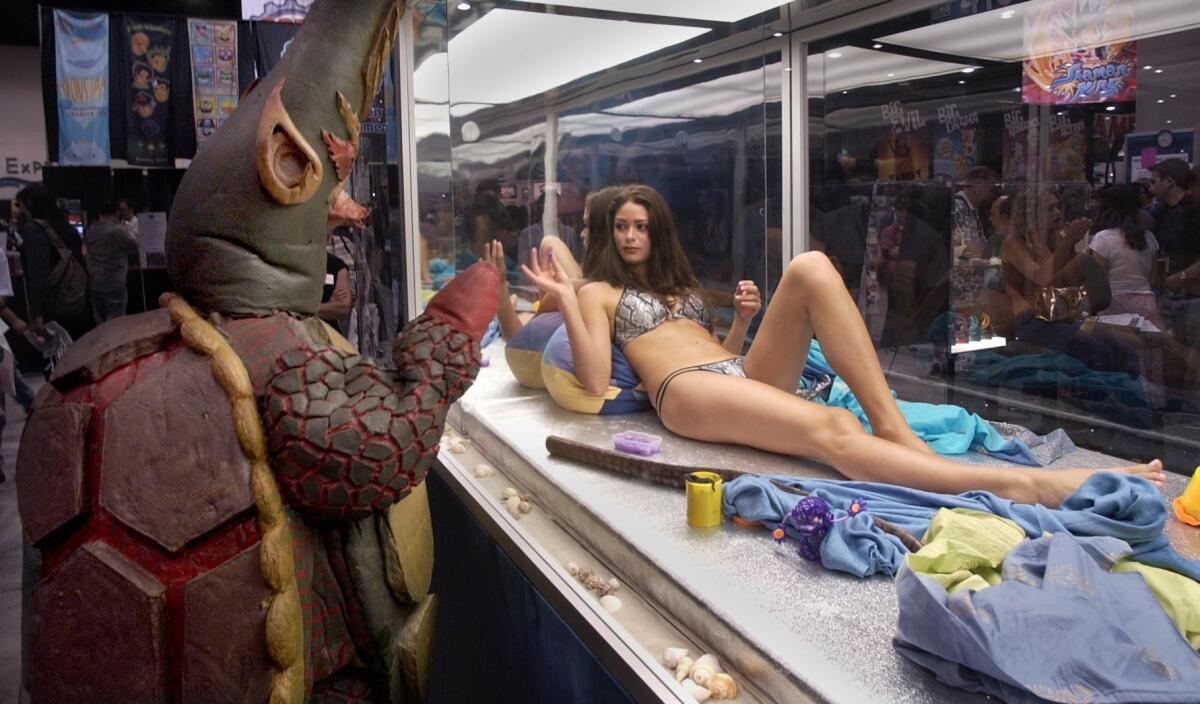 Vegetius, a character from the Kaiju action book series and DVD "Kaiju Big Battel," waves to Crystial Graham, a model representing the film "Species III Sexy Alien."