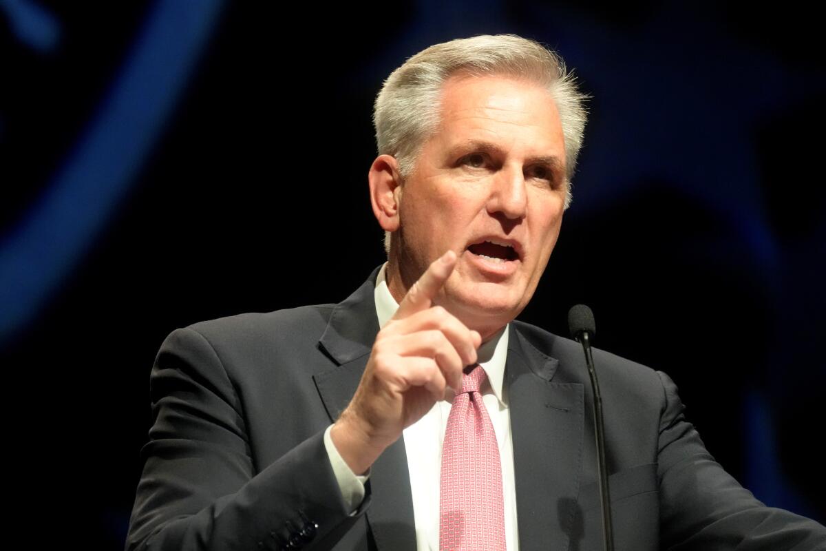 A man in a suit and tie gesturing and speaking into a microphone