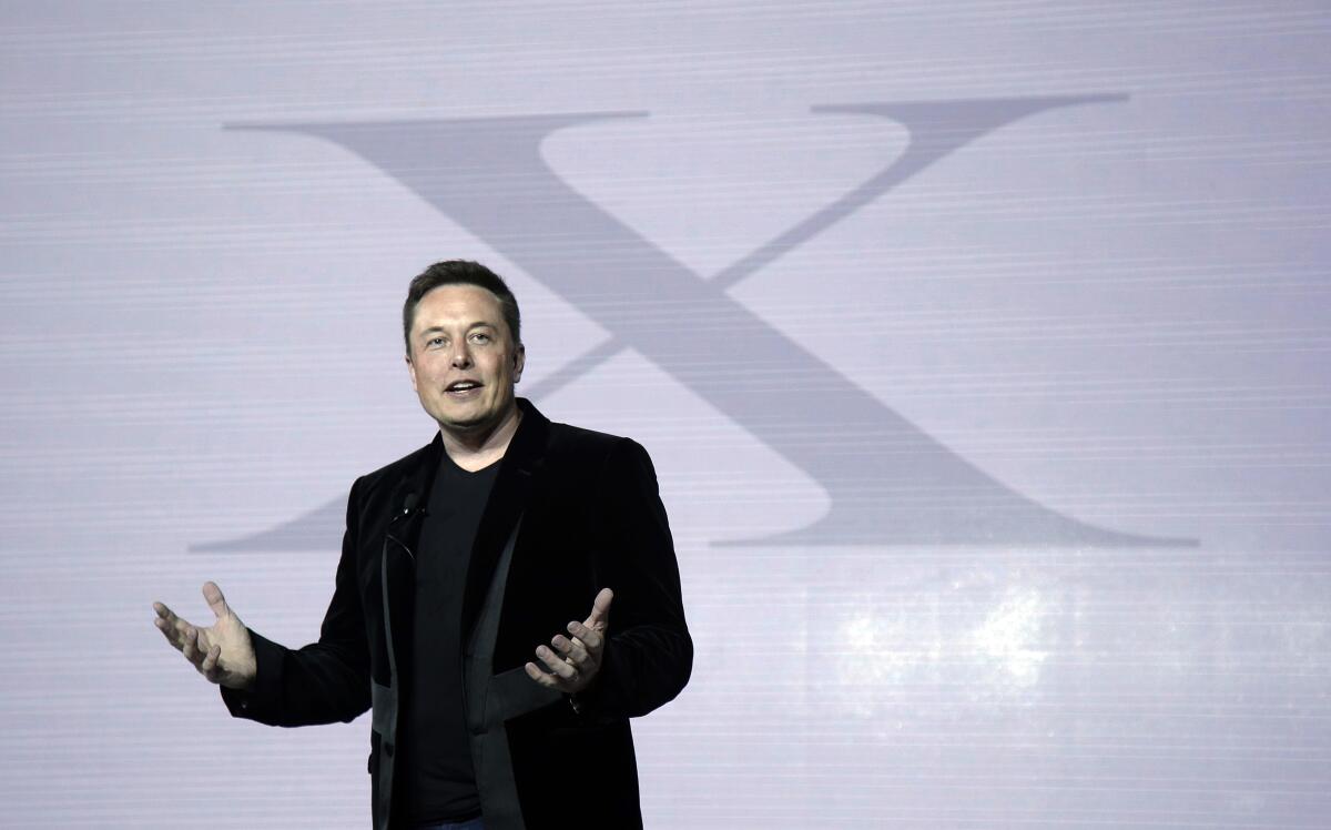 Elon Musk on a stage with a large X displayed on a background behind him