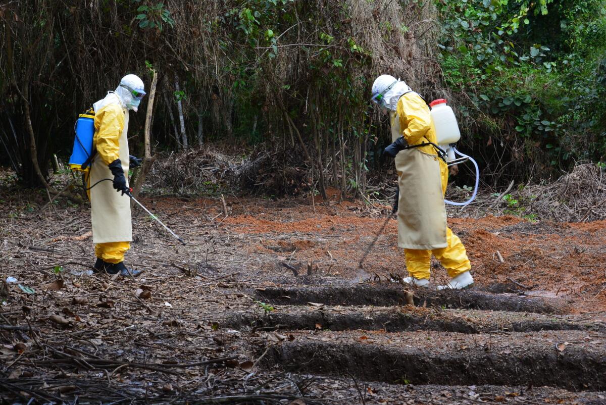 The burial team at the International Medical Corps Ebola treatment unit in Bong County, Liberia, sprays the grave of an Ebola victim with a chlorine disinfectant.
