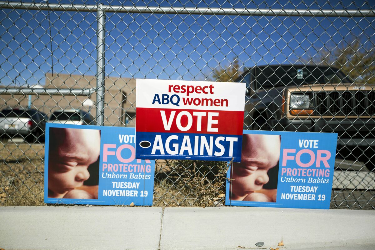 Signs advocating votes for and against a ban on late-term abortions hang on a fence outside a voting site at Eisenhower Middle School in Albuquerque.