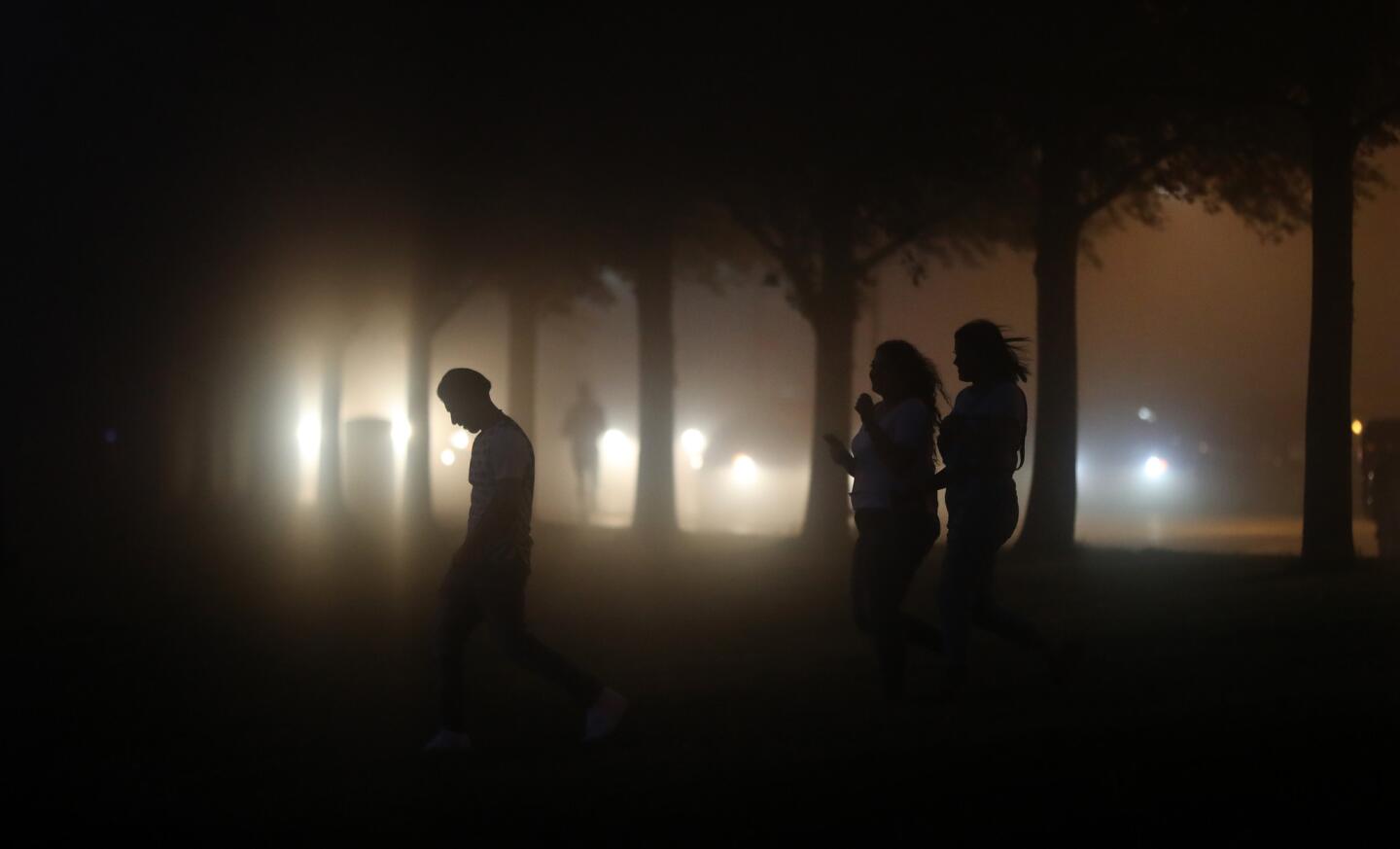 Three people walk along the lakefront as fog rolls into downtown on June 5, 2019.