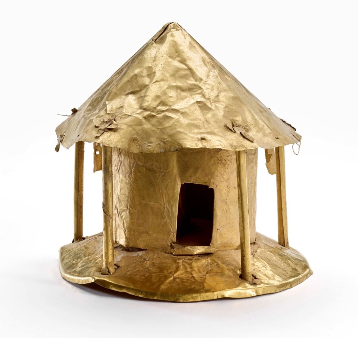 An Indigenous object made with gold alloy shows a circular building with a pitched roof.