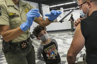 Orion Patron, 5,  watches as his father, Deputy Ronald Patron, is vaccinated at a COVID-19 mobile site in Pomona on March 5.