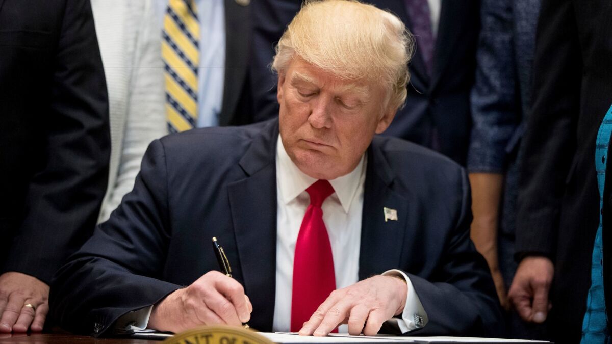 President Trump signs an executive order in the Roosevelt Room of the White House on Wednesday. Hours after officials said he was considering an order to leave NAFTA, he told Mexico and Canada the U.S. will stay put.