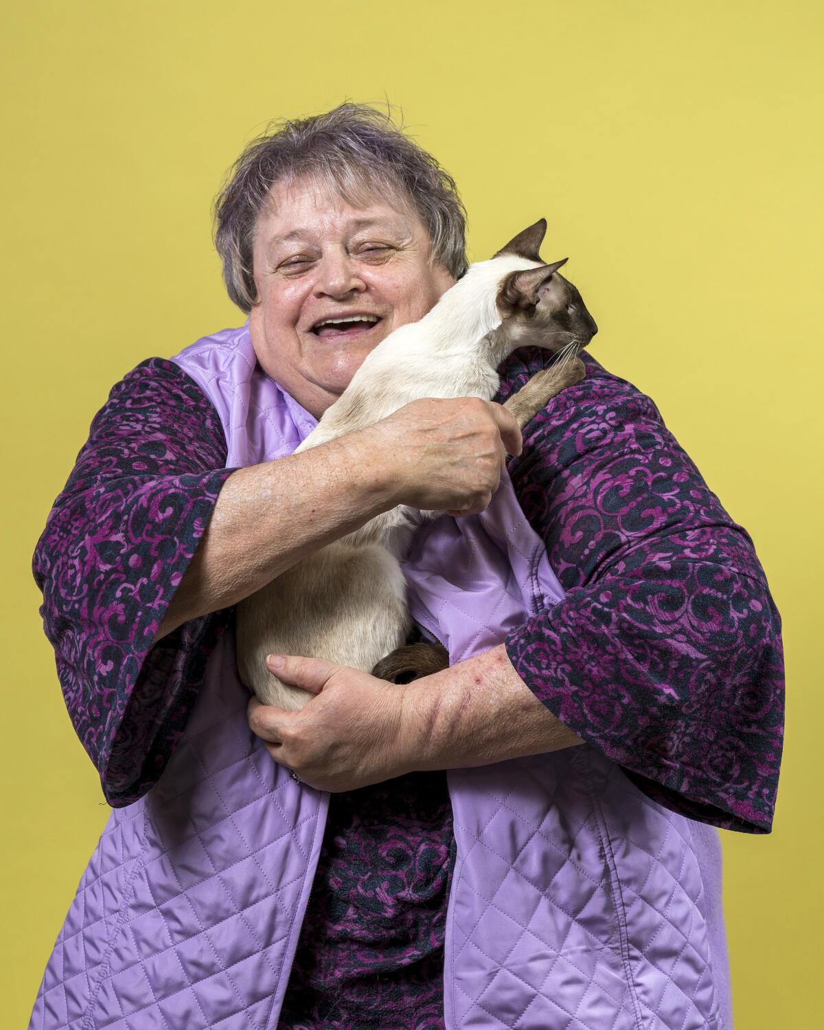June Colwell holds her Chocolate Point Siamese named Little Sis.