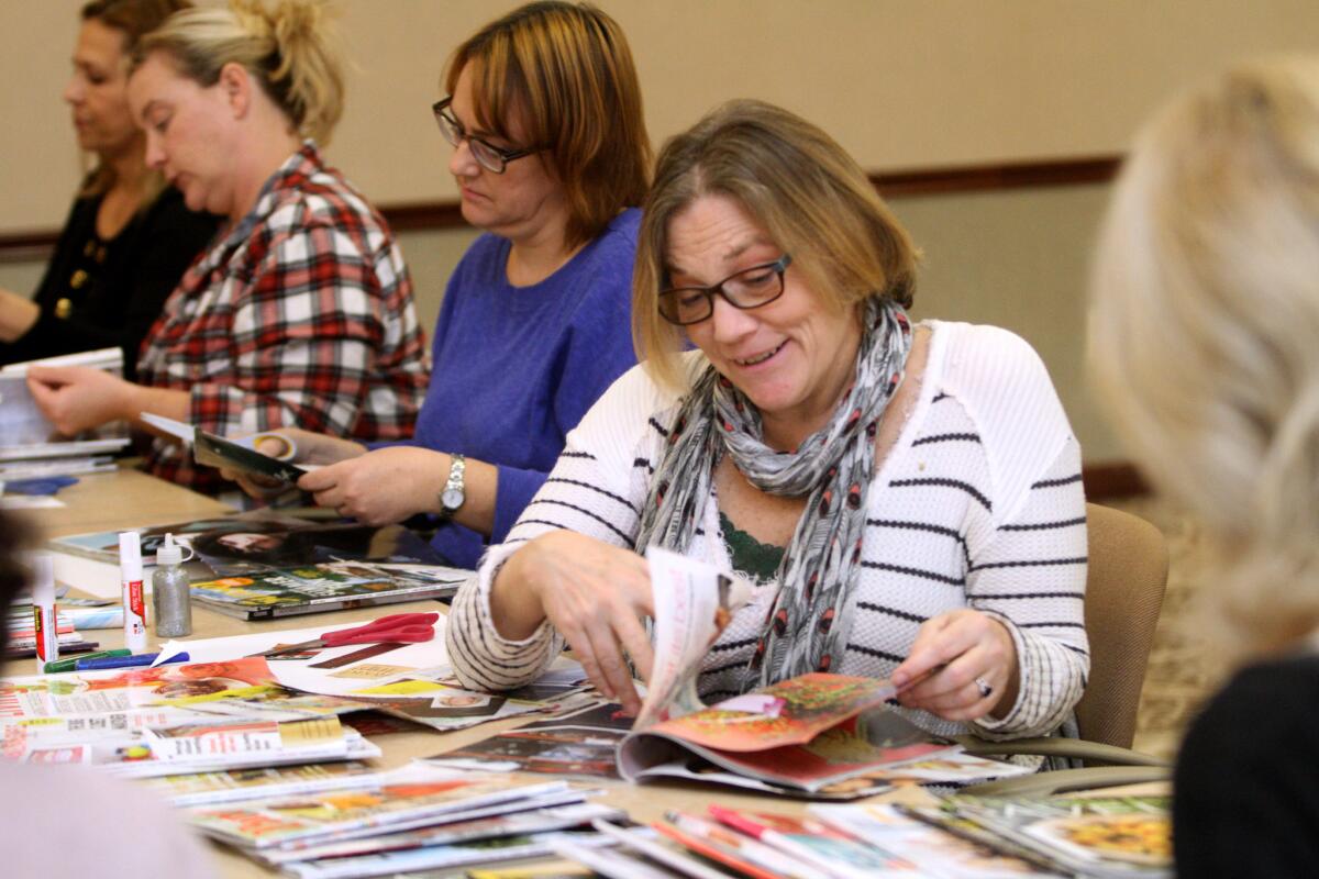 JoAnn Lowrie, center, of Sun Valley, and friend Lori Bender, left of center, thumb through magazines looking for items to cut out for their vision boards during Buena Vista Branch Library's vision board party in Burbank on Saturday, Jan. 16, 2016.