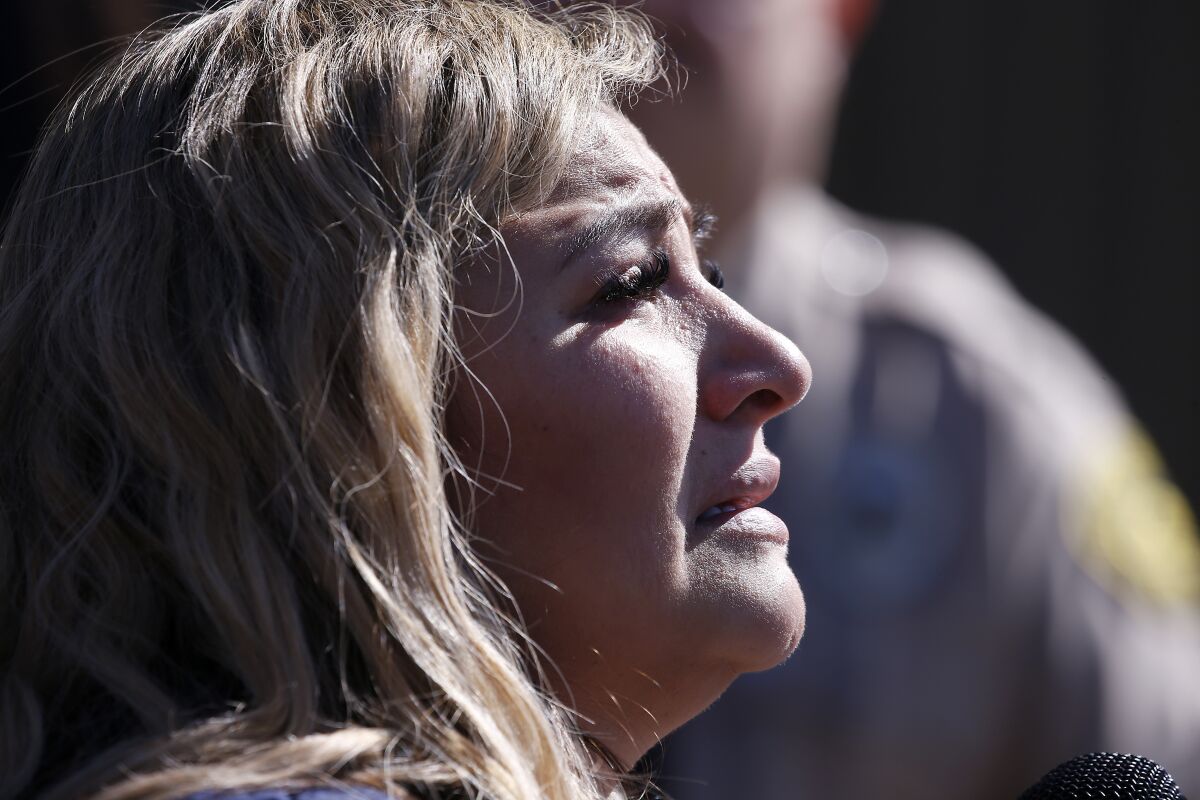 A close-up, profile view of a woman with blond hair speaking to a microphone, looking emotional.