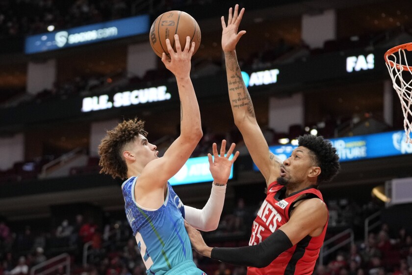 Charlotte Hornets guard LaMelo Ball , left, shoots as Houston Rockets center Christian Wood defends during the first half of an NBA basketball game, Saturday, Nov. 27, 2021, in Houston. (AP Photo/Eric Christian Smith)