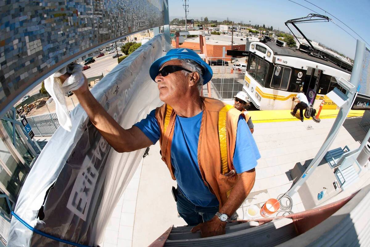 Metro contractor Alfred Lopez of California Neon Products spruces up artwork and signage at the Expo Line's Culver City station in advance of its official opening.