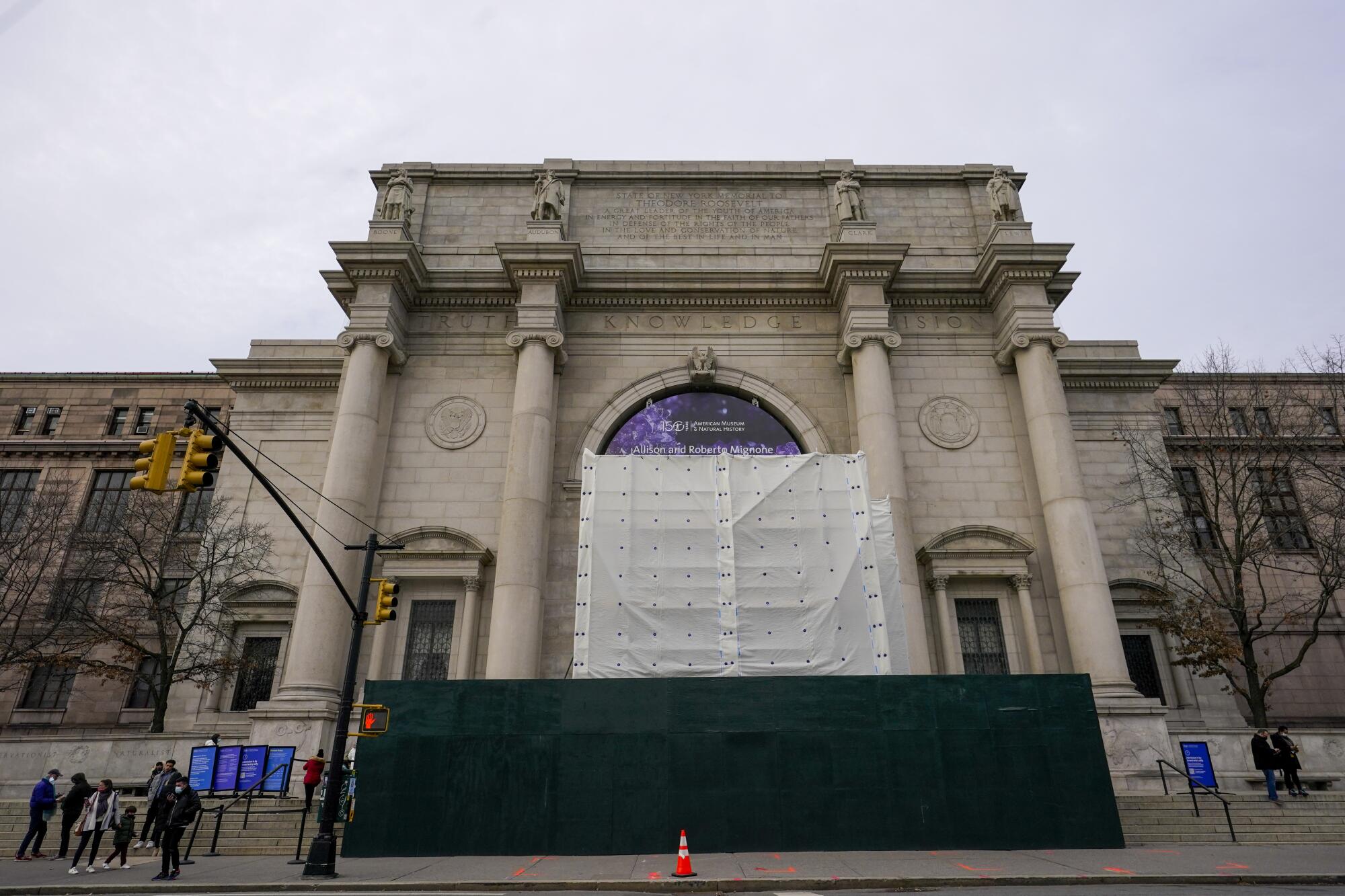 A scaffolding and tarp block views of a monument to Theodore Roosevelt before a Neoclassical building facade