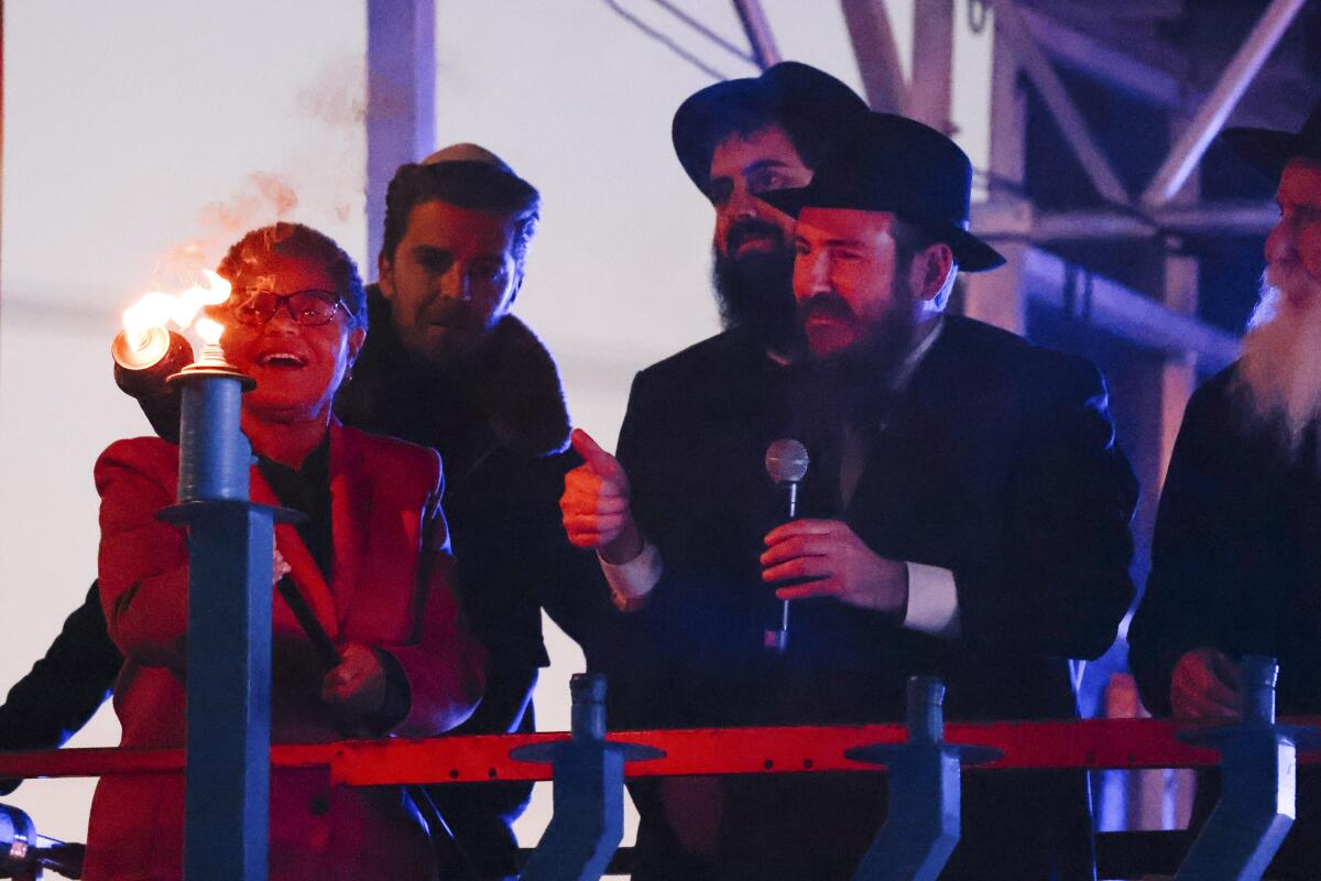 Mayor Karen Bass lights the Shamash of a menorah with community leaders.