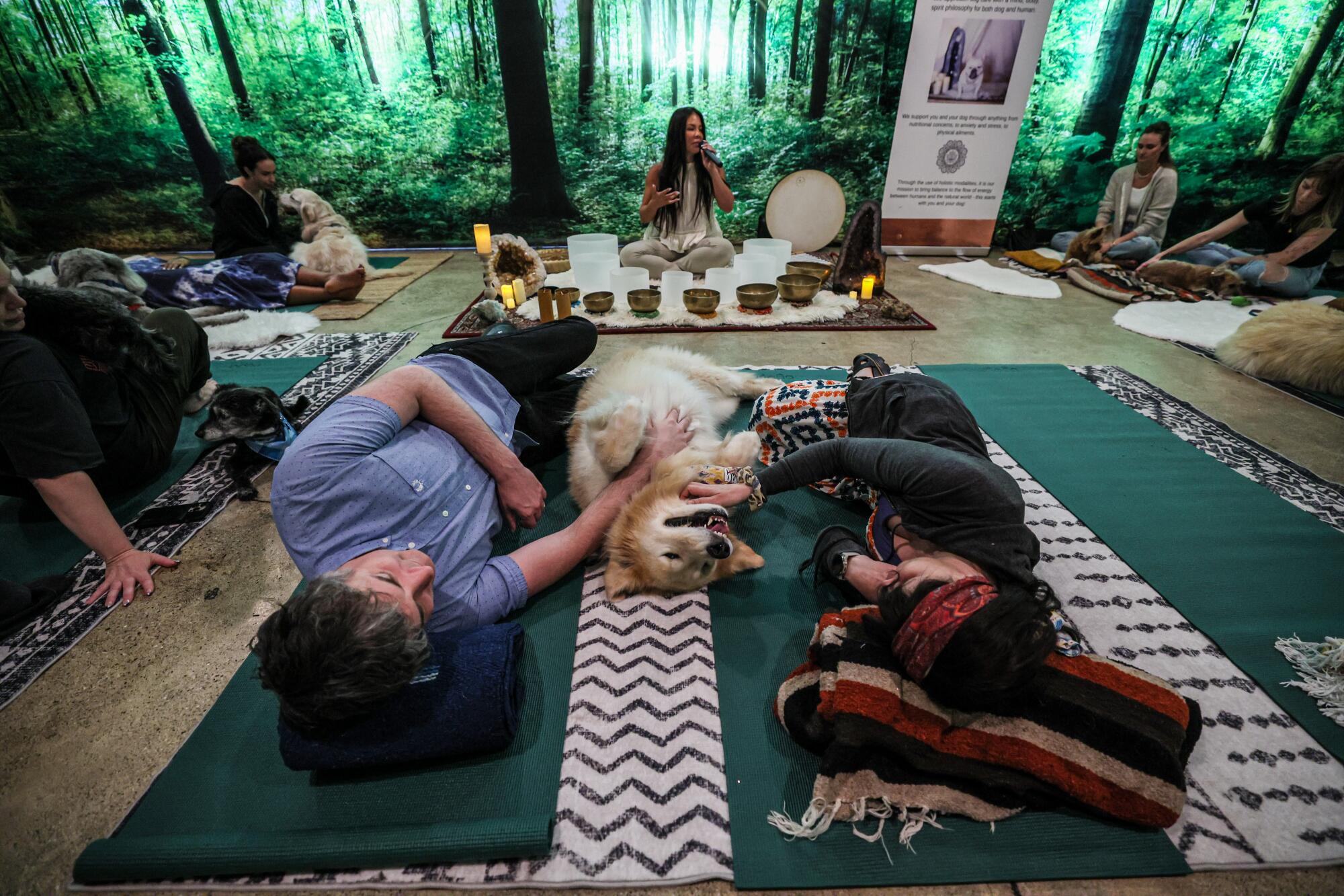 A dog relaxes on a yoga mat with his humans while a sound bath is underway.