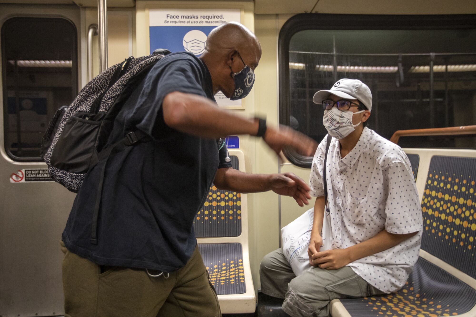 Two men talk on a Metro light rail car