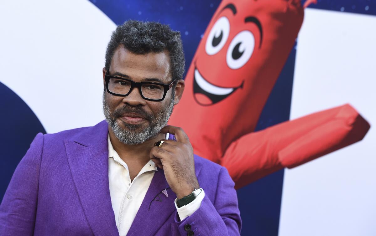 A man with a beard and glasses posing in a purple suit