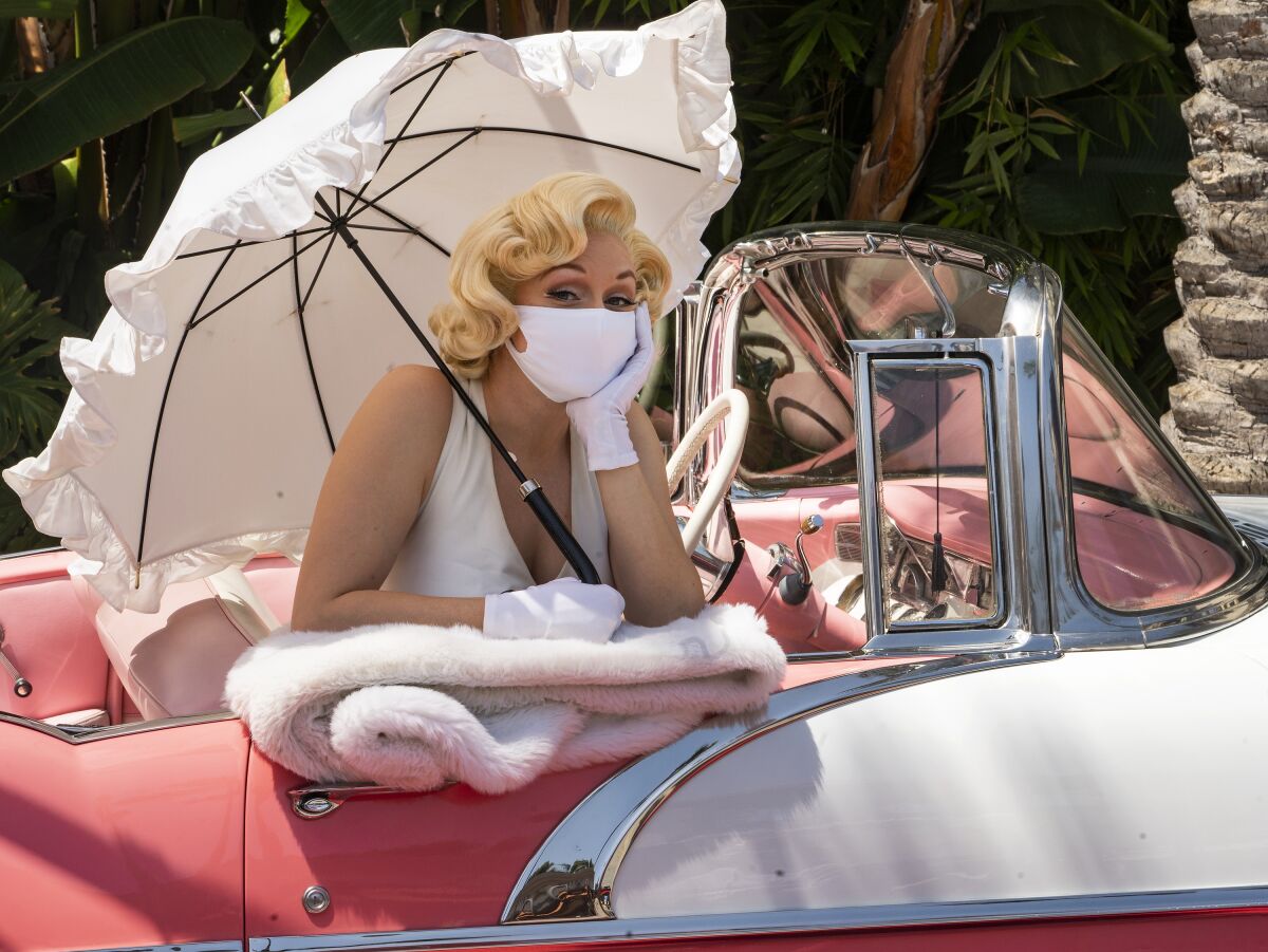 FILE - In this Friday, April 16, 2021, file photo, an actress playing a Marilyn Monroe character wears a face mask as she poses for pictures at Universal Studios Hollywood theme park in Los Angeles. The park officially reopens to the public at 25% capacity with COVID-19 protocols in place. California Gov. Gavin Newsom appeared disinclined Friday, June 4, 2021, to insert himself into the regulatory process for workplaces after a state safety board upset business groups by approving new rules that require all workers to wear masks unless everyone around them is vaccinated against the coronavirus, The revised rules, approved after a long and sometimes contentious meeting Thursday, eliminate social distancing requirements but run counter to Newsom's plan to "fully" reopen California in less than two weeks and allow vaccinated people to skip face coverings in nearly all situations. (AP Photo/Damian Dovarganes, File)