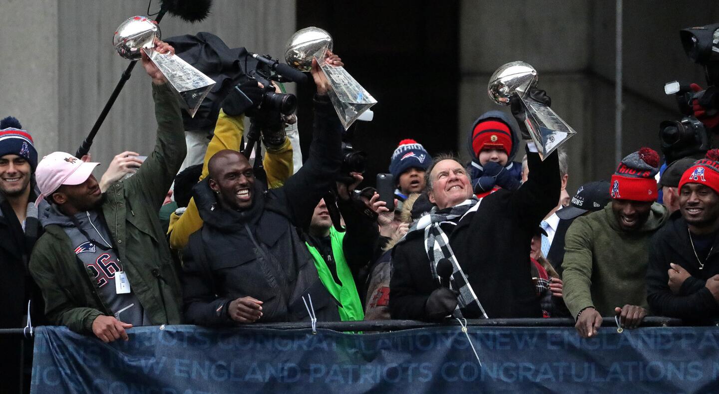 New England Patriots head coach Bill Belichick holds up the Lombardi trophies during today's rally at city hall plaza in Boston