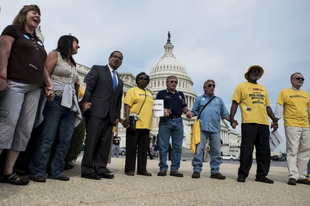 Rep. Keith Ellison (D-Minn.) and demonstrators hold hands on Capitol Hill in Washington on Oct. 3 to protest cuts to Social Security. In addition to Social Security, some have suggested that Medicare and Medicaid should should also be cut as part of any agreement on the federal budget.