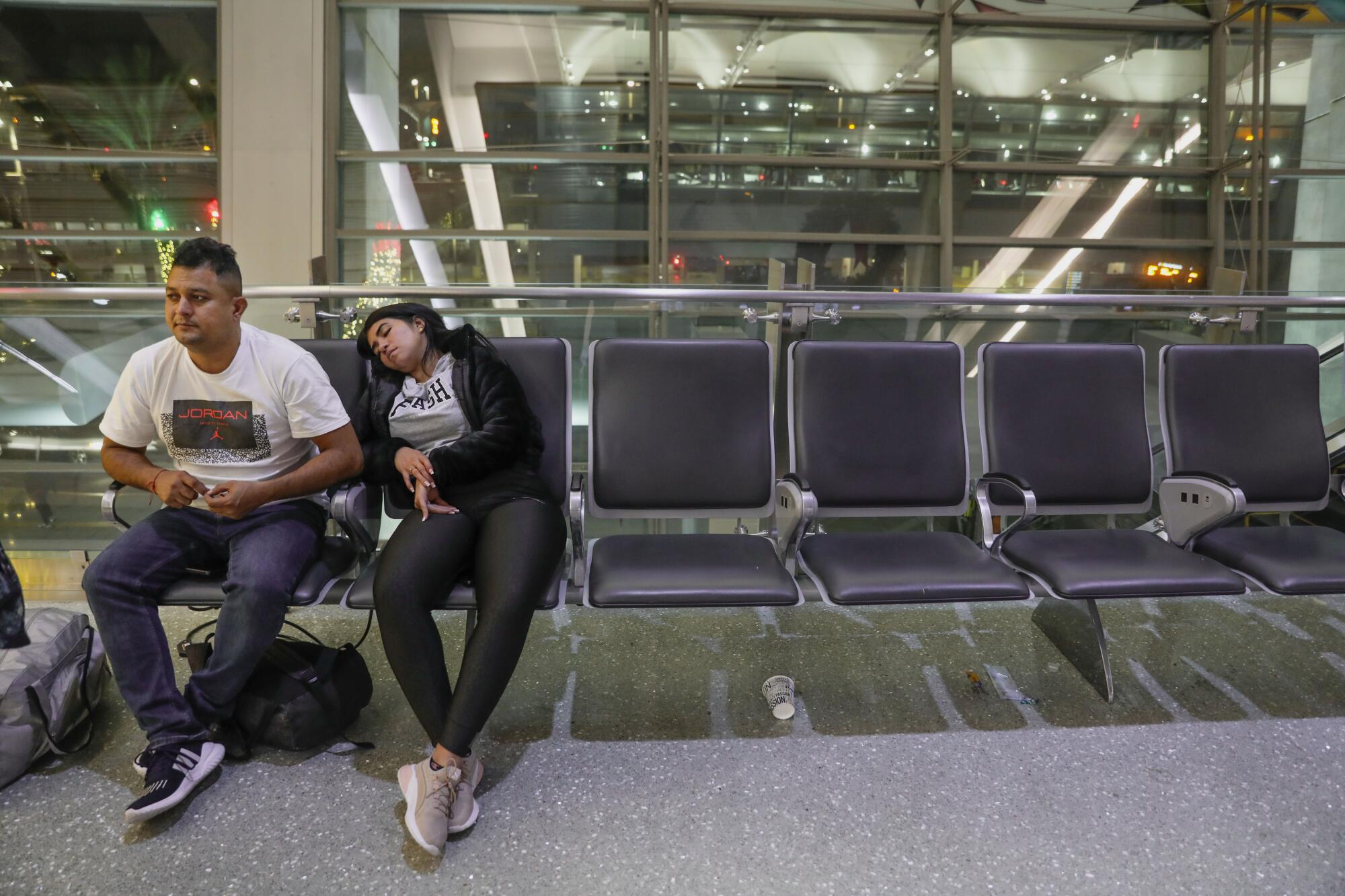 Kenny Ramierez and his partner, both from Venezuela, rest in a row of chairs.