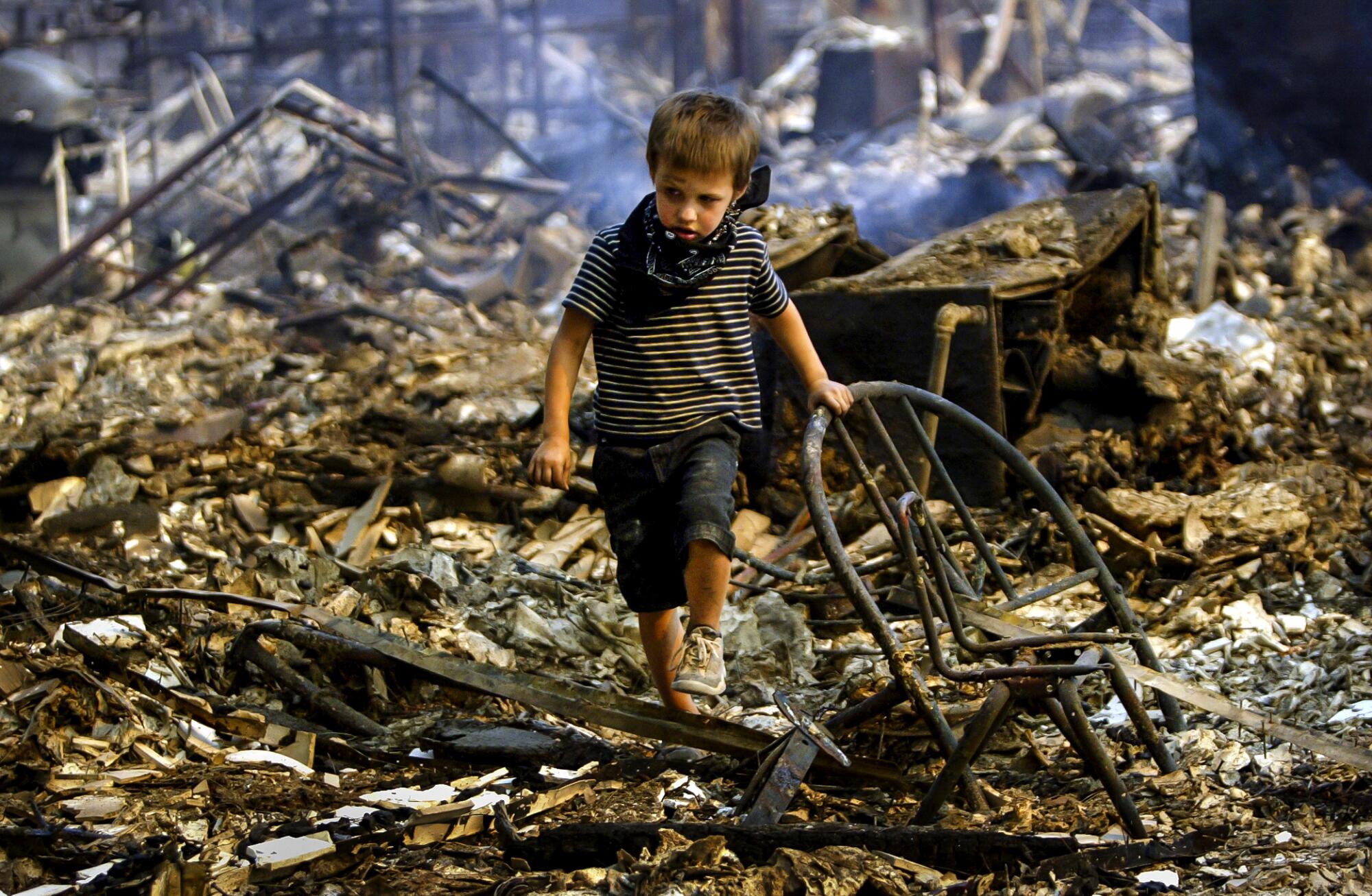 A child walks through the burned rubble of a home.