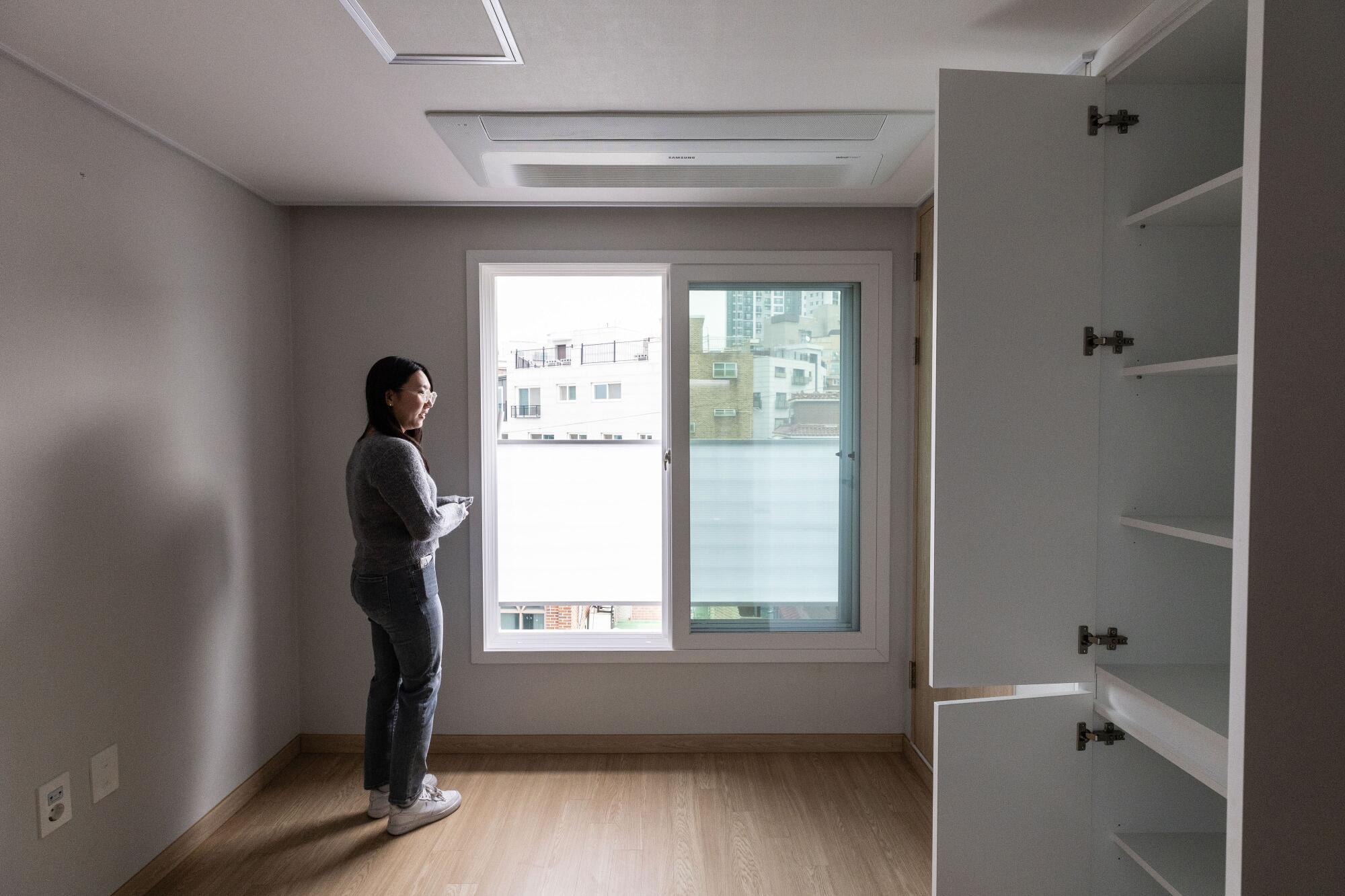 Kim Do-yeon abre a janela de seu quarto em seu novo apartamento.
