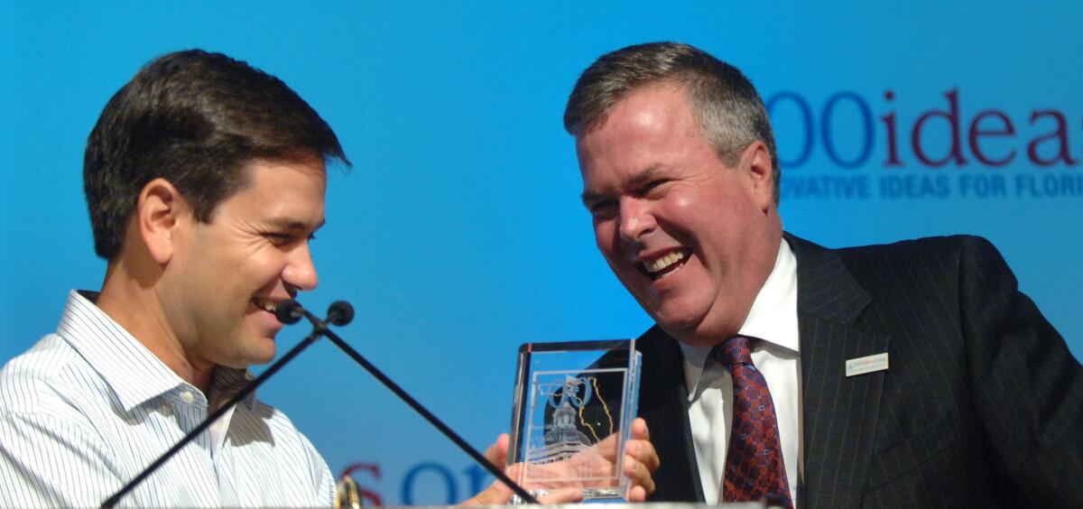 A photo taken Aug. 11, 2006 shows then-Gov. Jeb Bush laughing as incoming Florida House Speaker Marco Rubio presents him with an award at a Republican policy conference Rubio organized in Orlando, Fla.