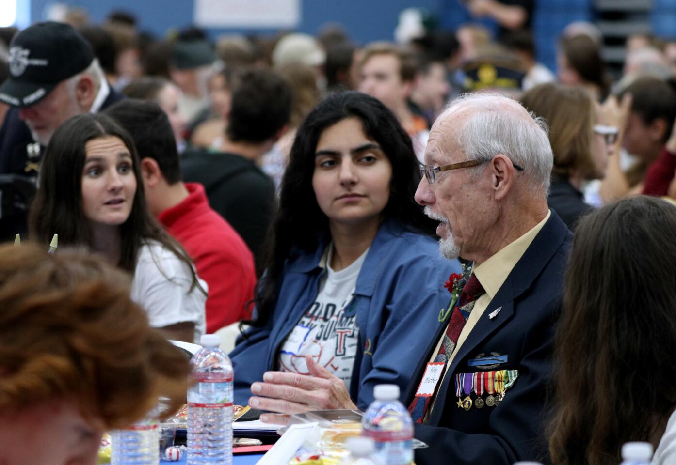 Sophomores Ryann McTague, left, and Niaz Namdar listen to Army veteran Kirby Matter, 75, of Fountain Valley at the Corona del Mar High School "Living History" luncheon on Thursday. Military veterans visited to share their experiences with students. Matter served during the Vietnam War.