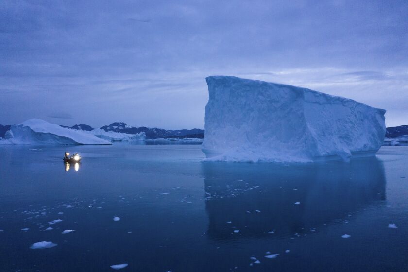 FILE - A boat navigates at night next to large icebergs in eastern Greenland on Aug. 15, 2019. Zombie ice from the massive Greenland ice sheet will eventually raise global sea level by at least 10 inches (27 centimeters) on its own, according to a study released Monday, Aug. 29, 2022. Zombie or doomed ice is still attached to thicker areas of ice, but it’s no longer getting fed by those larger glaciers. (AP Photo/Felipe Dana, File)