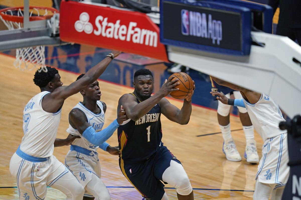 New Orleans Pelicans' Zion Williamson goes to the basket against Lakers guard Dennis Schroder and forward Devontae Cacok.