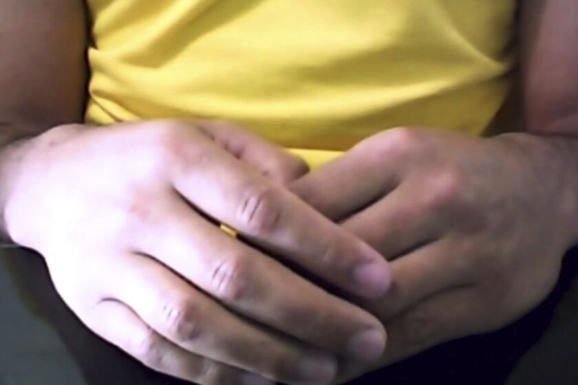 This mage made from video shows the hands of a Brazilian man who was infected with the AIDS virus and has shown no sign of it for more than a year since he stopped HIV medicines after an intense experimental drug therapy aimed at purging hidden, dormant virus from his body, doctors reported Tuesday, July 7, 2020. “I’m very moved because it’s something that millions of people want,” said the 35-year-old man, whose spoke to The Associated Press on condition that his name not be published. (Federica Narancio/Zoom via AP)