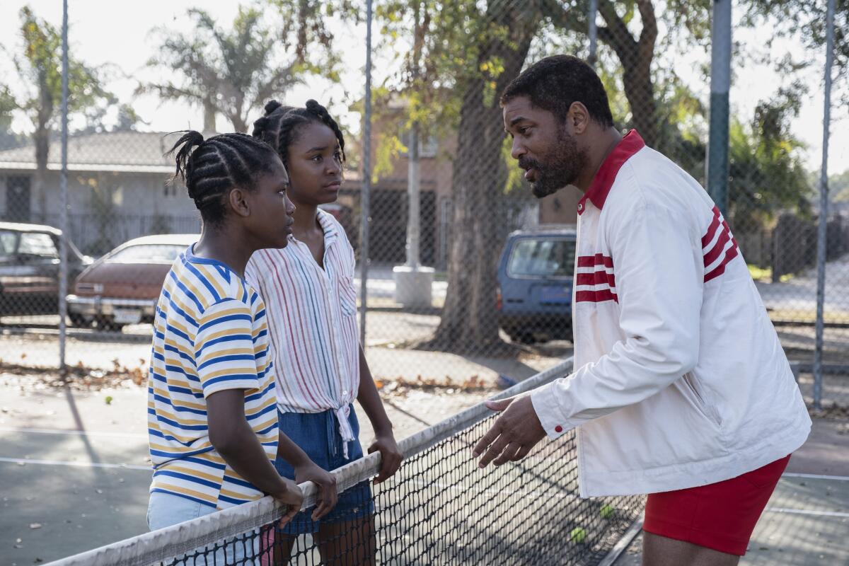 Will Smith with two girls on a tennis court in a scene from "King Richard." 