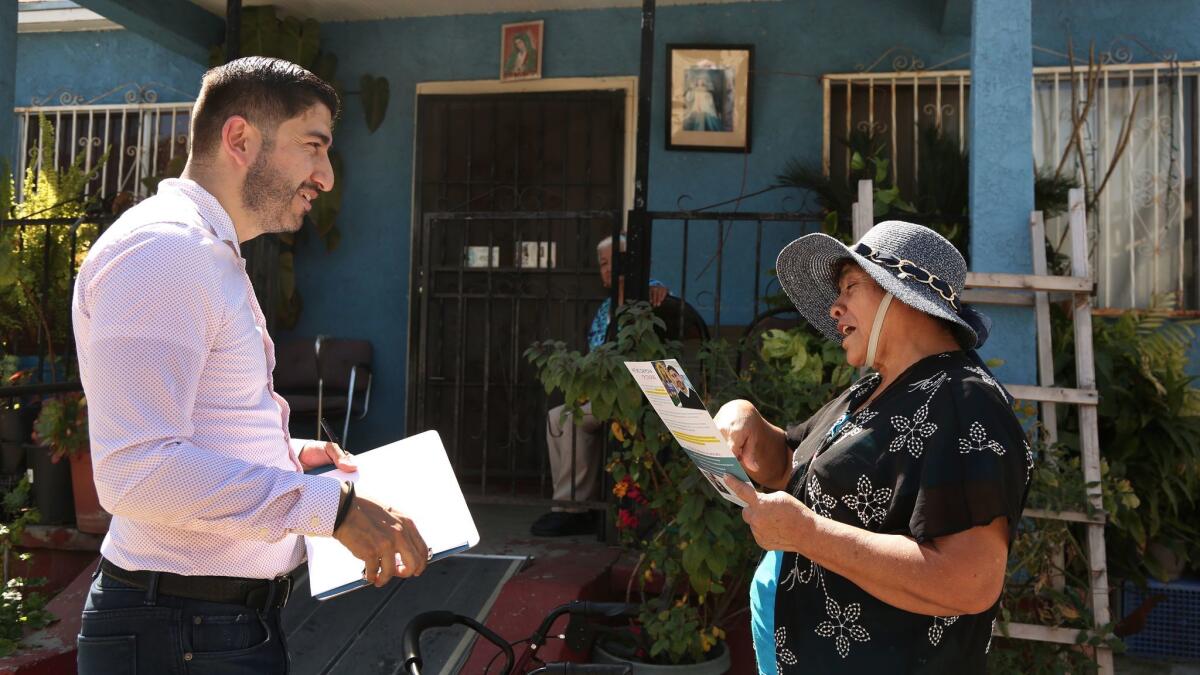 Congressional candidate Arturo Carmona talks with Consuelo Lopez, 71, as he makes his way through an East Los Angeles neighborhood in mid-March. (Rick Loomis / Los Angeles Times)