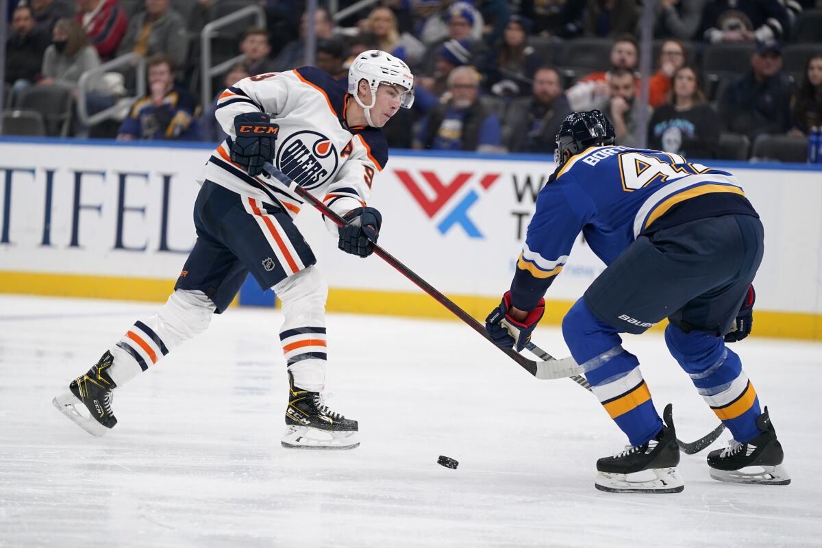 Edmonton Oilers' Ryan Nugent-Hopkins, left, shoots past St. Louis Blues' Robert Bortuzzo during the third period of an NHL hockey game Sunday, Nov. 14, 2021, in St. Louis. (AP Photo/Jeff Roberson)