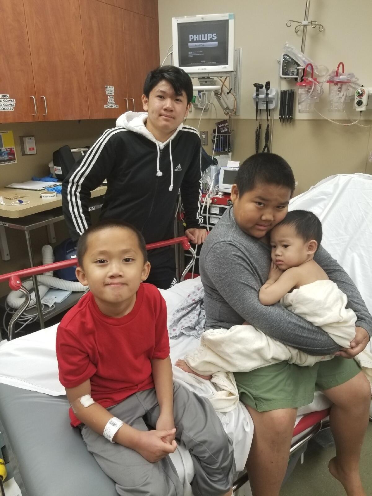 The Phommathep boys of Rancho Tehama: Jake, 6, front, was shot in the foot; John Jr., 10, who was shot in the calf, holds Nikos, 2, who was cut by glass; Tristan, 14, standing, escaped injury. Their mother was shot four times and survived.