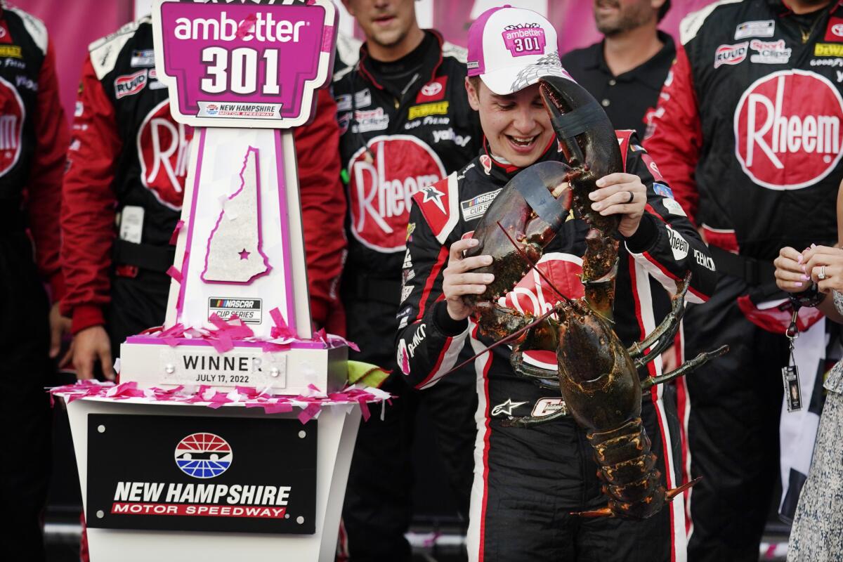 Christopher Bell holds up a giant lobster while celebrating after winning a NASCAR Cup Series auto race at the New Hampshire Motor Speedway, Sunday, July 17, 2022, in Loudon, N.H. (AP Photo/Charles Krupa)