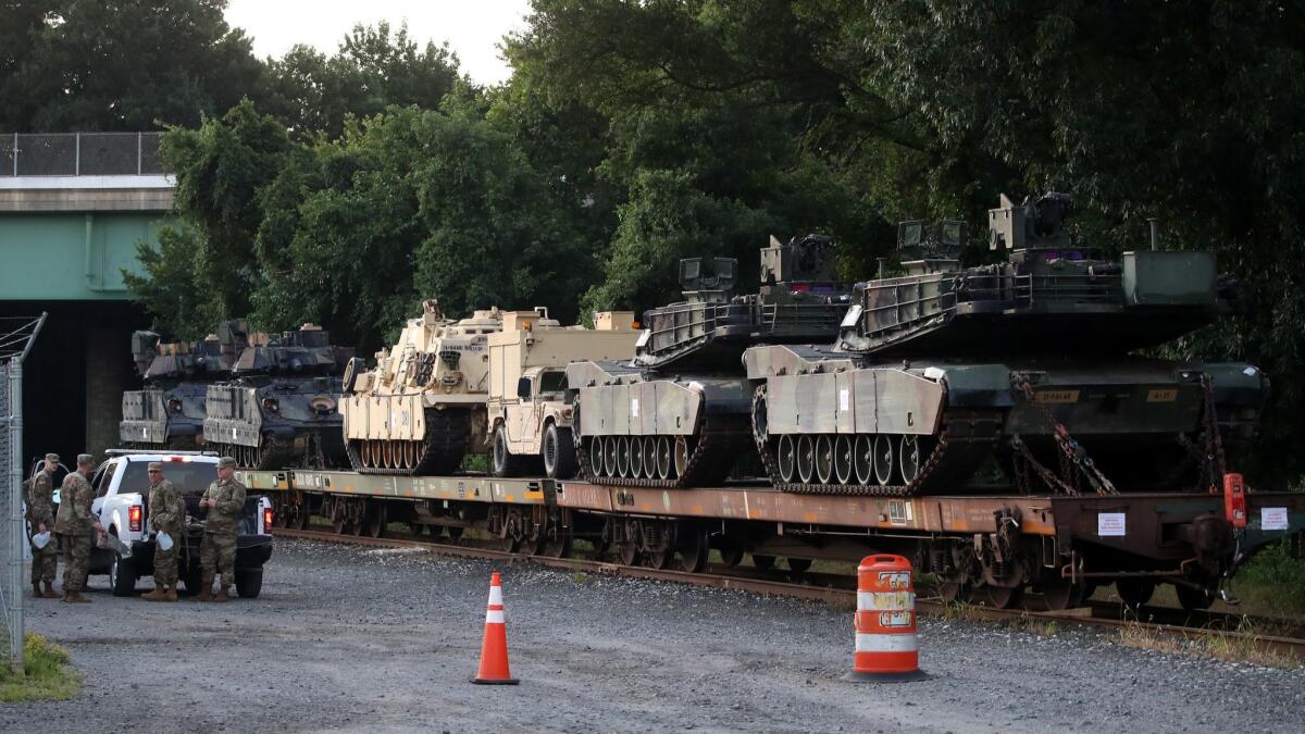 Two M1A1 Abrams tanks and other military vehicles sit on guarded rail cars at a Washington railyard on July 2.