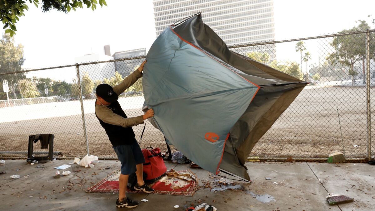 A homeless man packs up his tent as a city sanitation crew arrives for a cleanup.
